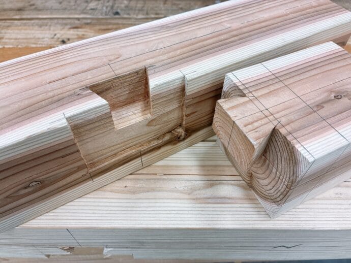 Stack of planed pine boards with pencil lines and notches for joinery.