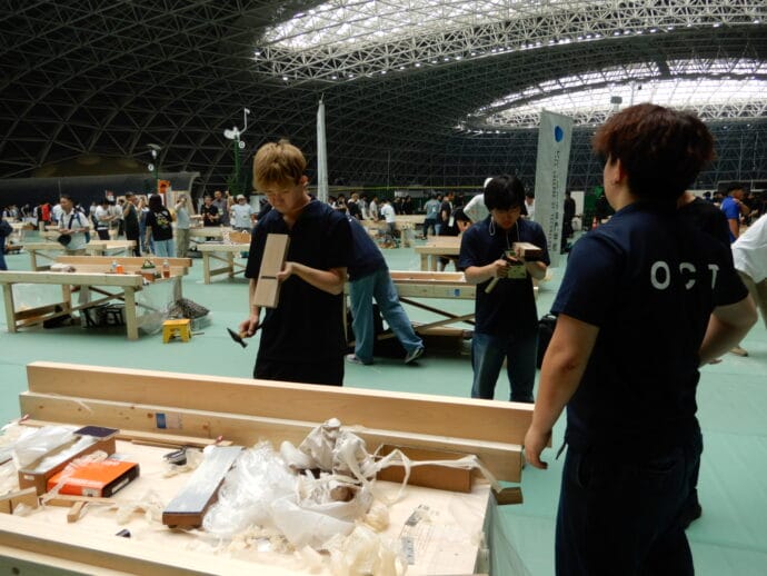 Workshop scene in a large hall with students building wooden benches and tools on work tables